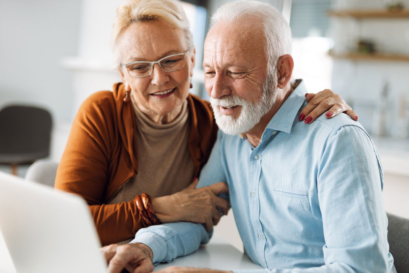 elderly couple discussing dental options together on computer