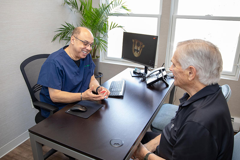 Doctor showing patient implant model to discuss dental implant information