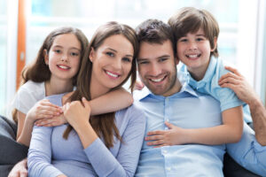 a happy family of four smiling because they have been treated for their family dentistry needs.